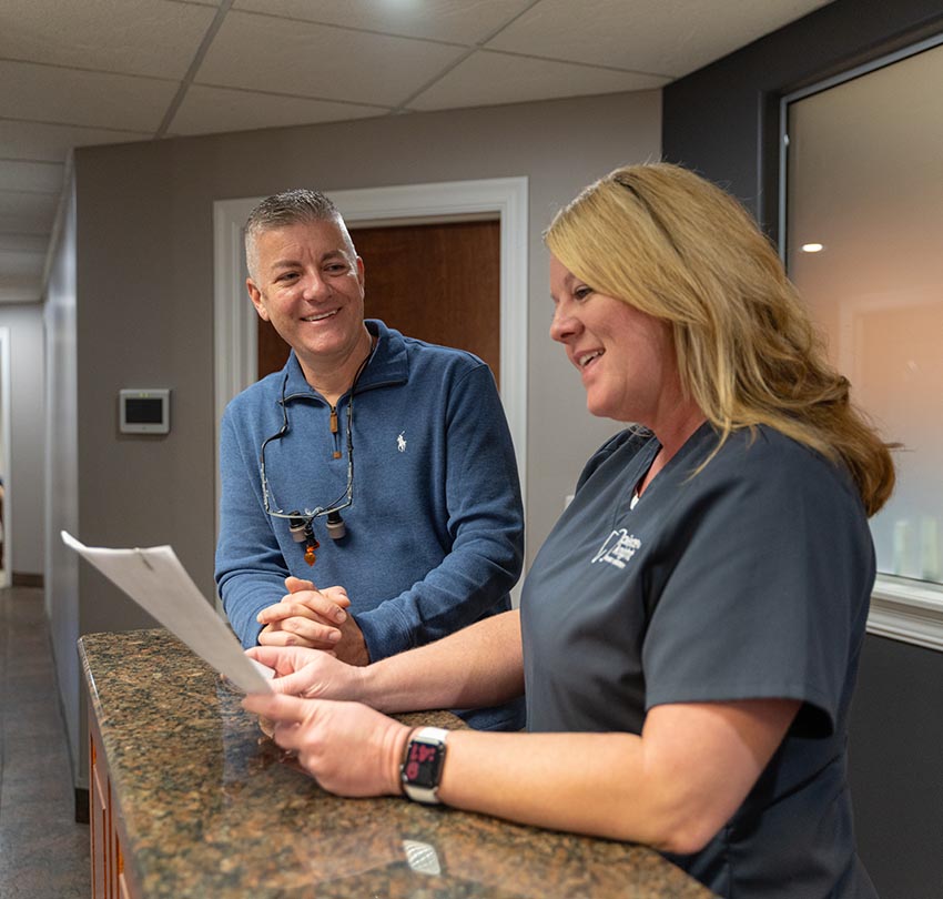 Dr. Robert Pierce talks to a female dental staff member at the counter inside Pierce & Knight Family Dentistry office